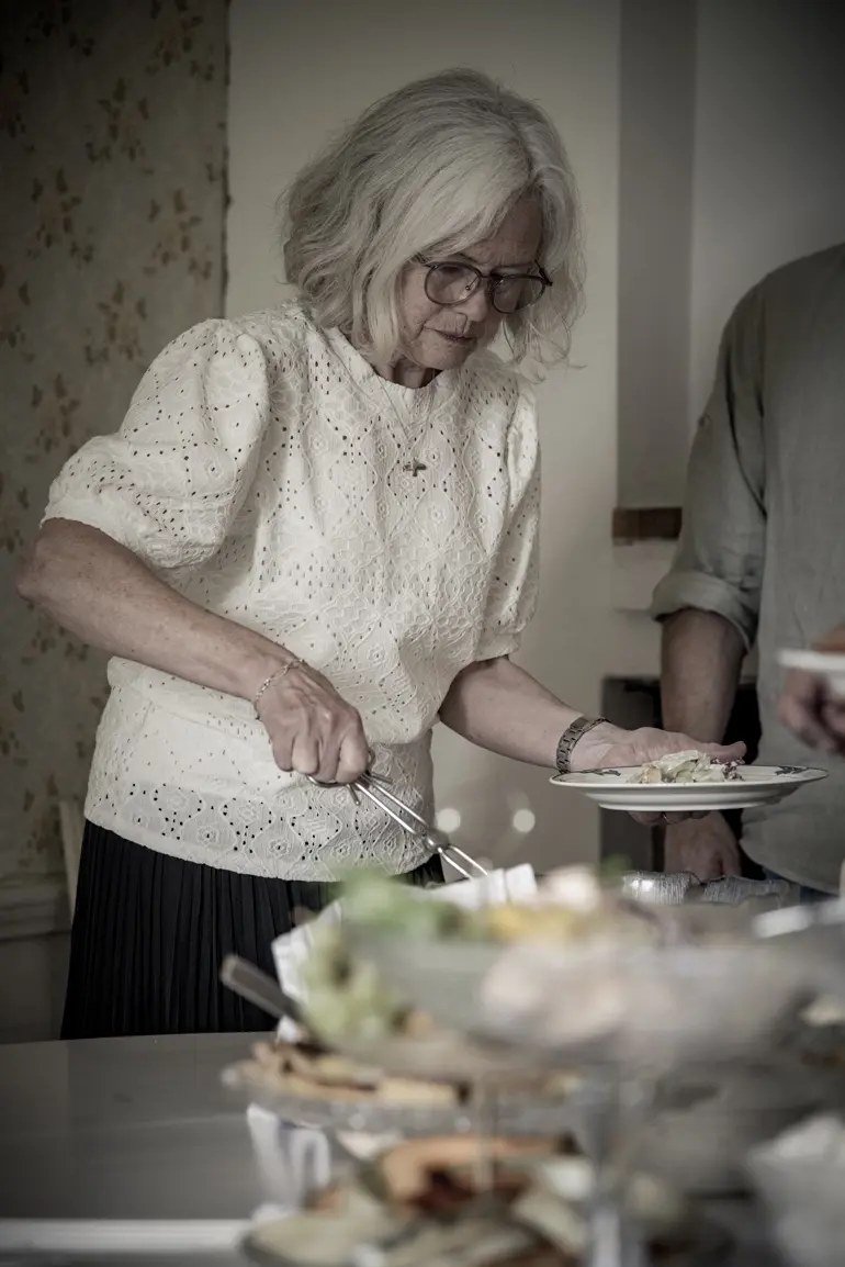 en kvinna tar mat av den uppdukade lunchen på Ruders egendom