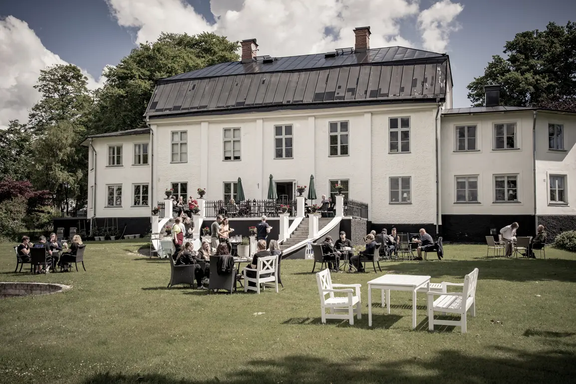 gäster på Ruders som sitter i trädgården och på terassen och äter lunch